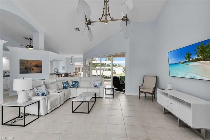 Living area with a ceiling fan, high vaulted ceiling, and light tile patterned floors