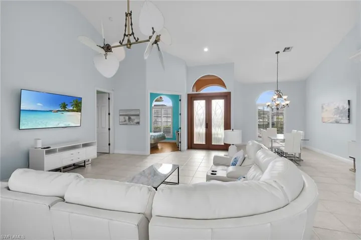 Living room featuring a chandelier, light tile patterned floors, french doors, recessed lighting, and high vaulted ceiling