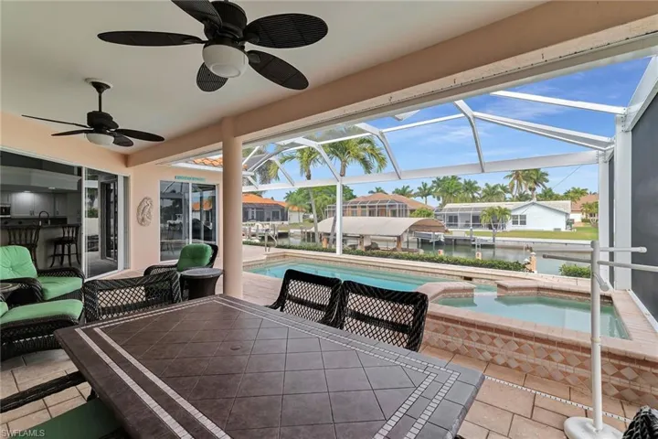 View of patio / terrace featuring outdoor dining area, a sunroom, a lanai, a water view, and a ceiling fan