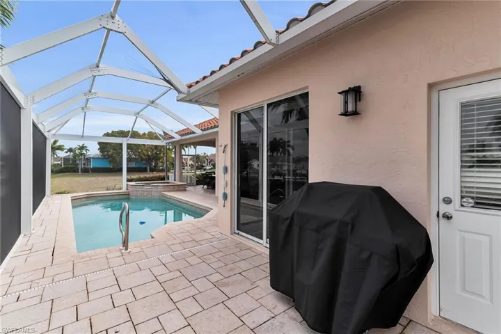 View of pool featuring area for grilling, a patio area, glass enclosure, a sunroom, and a pool with connected hot tub