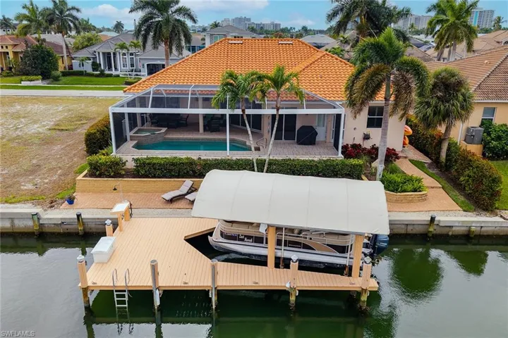 Dock with boat lift, a water view, glass enclosure, an outdoor pool, and a sunroom