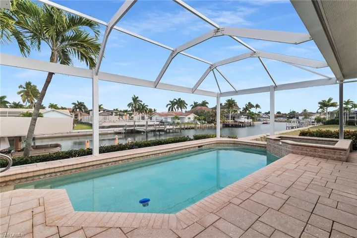 View of swimming pool featuring a sunroom, a water view, a lanai, a patio area, and a pool with connected hot tub