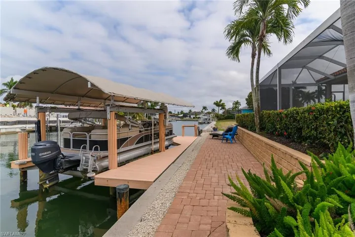 Dock featuring boat lift, a water view, glass enclosure, and a sunroom