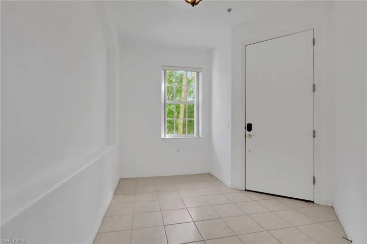 Foyer entrance with light tile patterned floors and baseboards