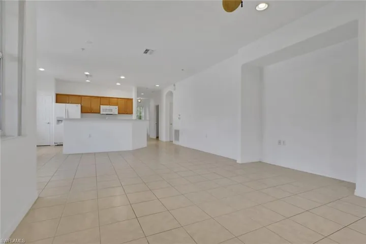 Unfurnished living room with arched walkways, recessed lighting, and light tile patterned floors