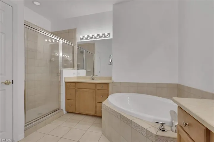 Full bathroom featuring vanity, a garden tub, a stall shower, and light tile patterned floors