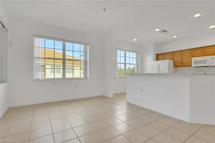 Kitchen featuring white appliances, light countertops, recessed lighting, brown cabinets, and light tile patterned floors
