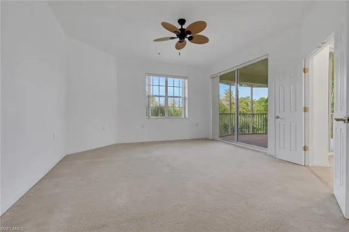 Empty room featuring light colored carpet and a ceiling fan