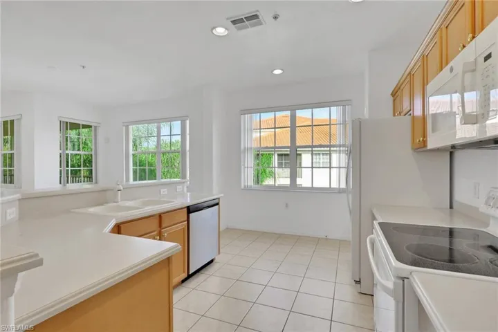 Kitchen featuring white appliances, light countertops, light tile patterned floors, and recessed lighting