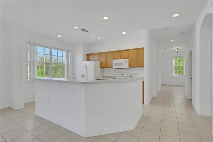 Kitchen featuring light countertops, white appliances, recessed lighting, light tile patterned flooring, and a kitchen island