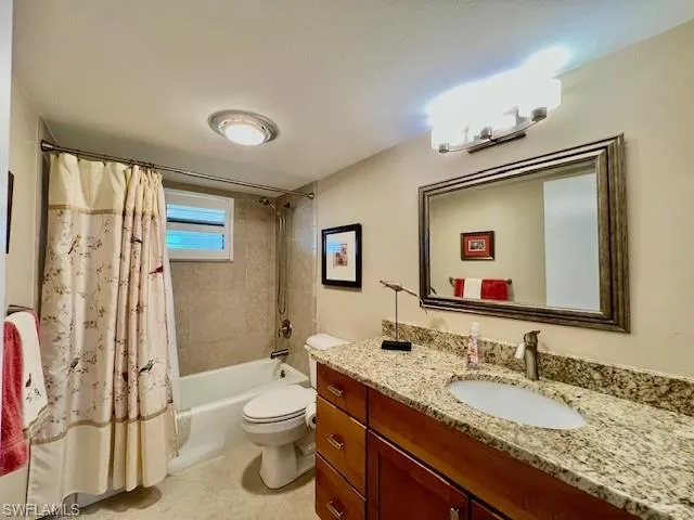 Full bathroom with vanity, shower / bath combination with curtain, and toilet