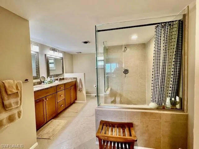 Bathroom with tiled shower, vanity, and tile patterned flooring