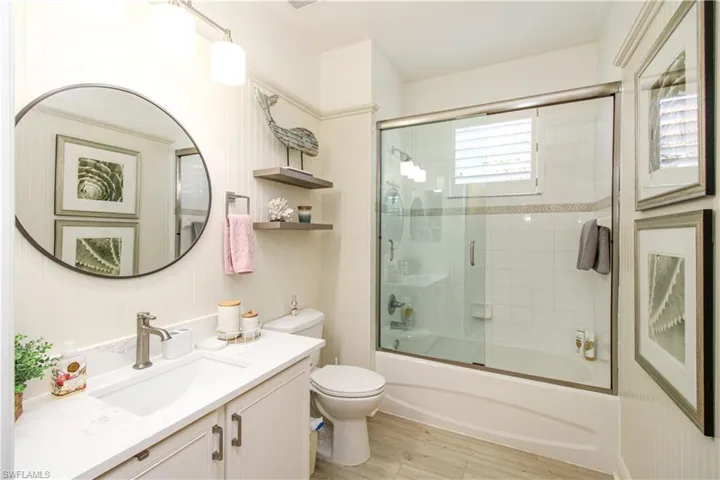 Full bathroom with toilet, combined bath / shower with glass door, vanity, and wood-type flooring