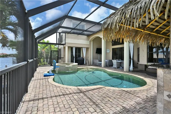 Screened outdoor living area featuring a freeform swimming pool with integrated spa