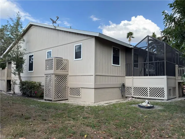 View of side of home featuring a sunroom, a yard, a lanai, and a wooden deck