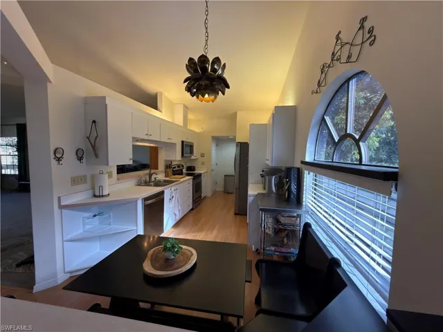 Kitchen featuring light countertops, stainless steel appliances, light wood-style floors, white cabinetry, and healthy amount of natural light
