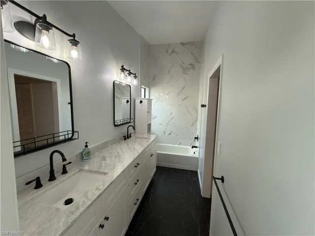 Bathroom featuring double vanity and dark marble finish floors