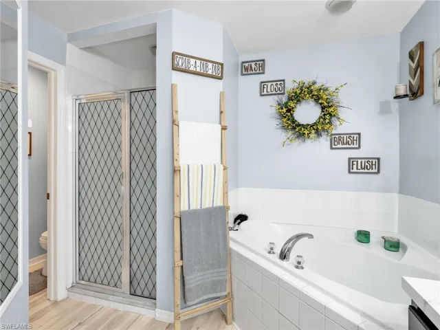 Bathroom with a shower stall, a garden tub, vanity, and light wood-type flooring
