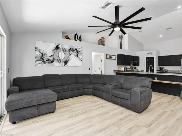 Living room with ceiling fan, lofted ceiling, light wood-type flooring, and recessed lighting
