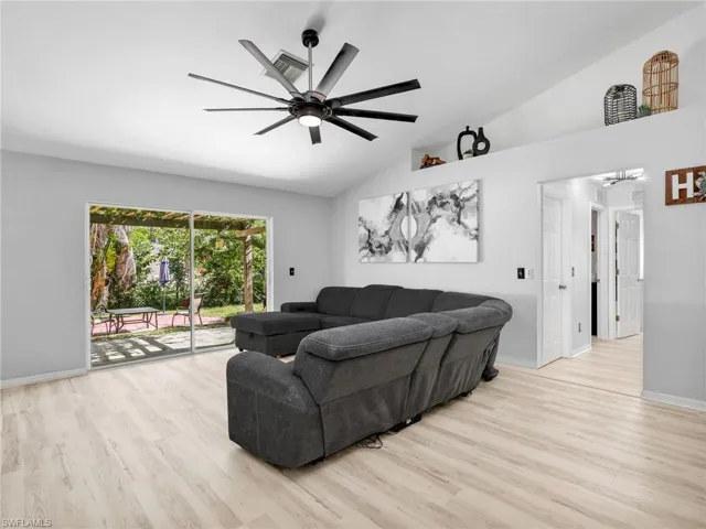 Living area with light wood-style flooring, ceiling fan, and lofted ceiling