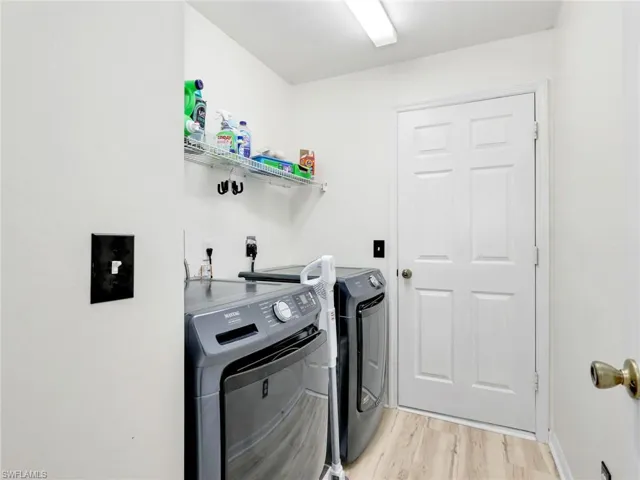Laundry area with light wood-type flooring and separate washer and dryer