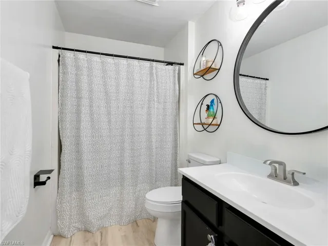 Full bath with vanity, light wood-type flooring, and a shower with shower curtain