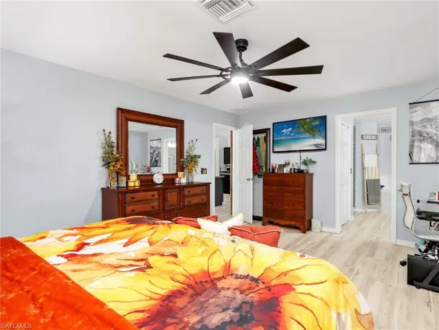 Bedroom with light wood-style floors, ceiling fan, and a desk