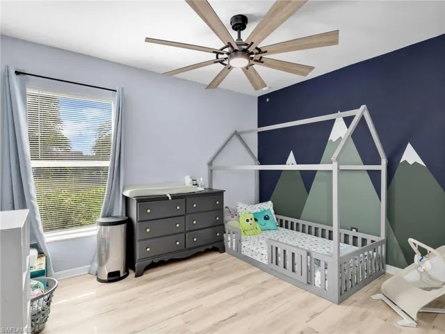 Bedroom with light wood-style flooring, a ceiling fan, and a nursery area