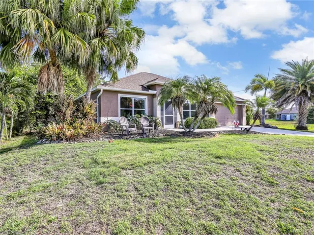 Ranch-style house featuring a garage, stucco siding, a front yard, and driveway