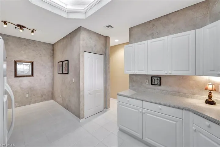 Kitchen with white refrigerator, white cabinetry, and light tile patterned floors