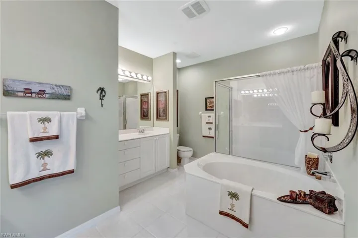 Full bathroom featuring vanity, toilet, shower with separate bathtub, and tile patterned flooring