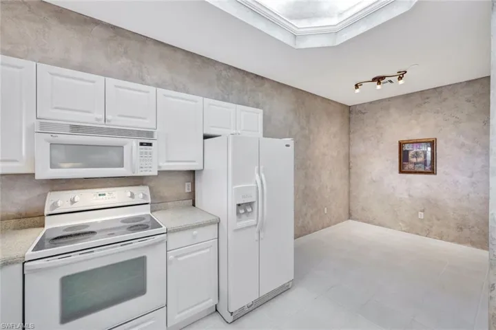 Kitchen featuring crown molding, white cabinets, and white appliances