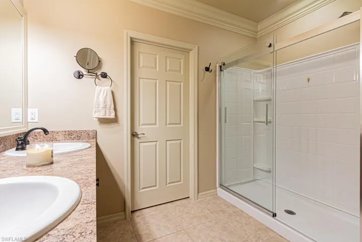 Bathroom with tile patterned flooring, crown molding, vanity, and an enclosed shower