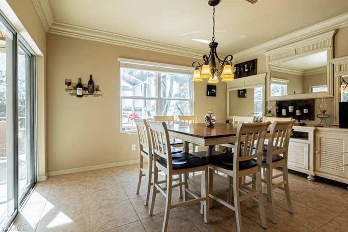 Tiled dining space featuring an inviting chandelier, crown molding, and a wealth of natural light