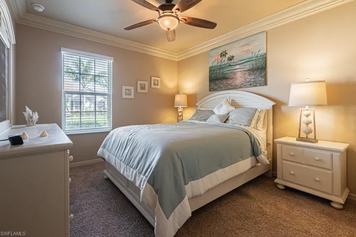 Bedroom with dark colored carpet, ceiling fan, and crown molding