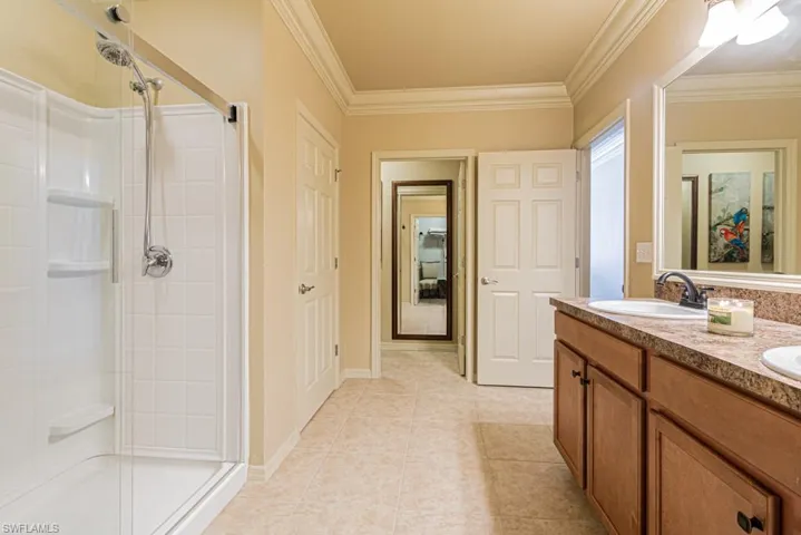 Bathroom with crown molding, vanity, an enclosed shower, and tile patterned flooring