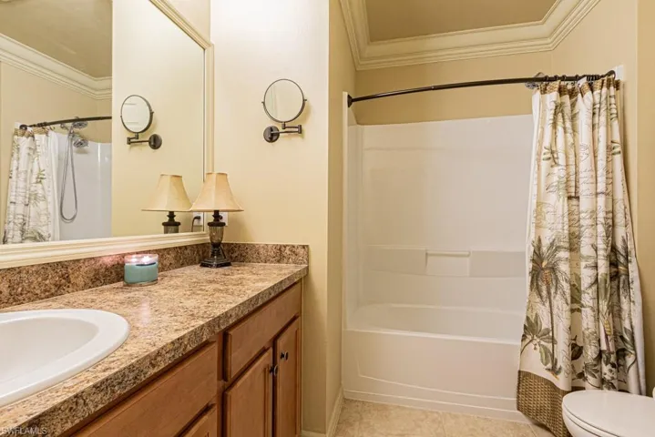 Full bathroom featuring tile patterned floors, toilet, crown molding, shower / tub combo, and vanity