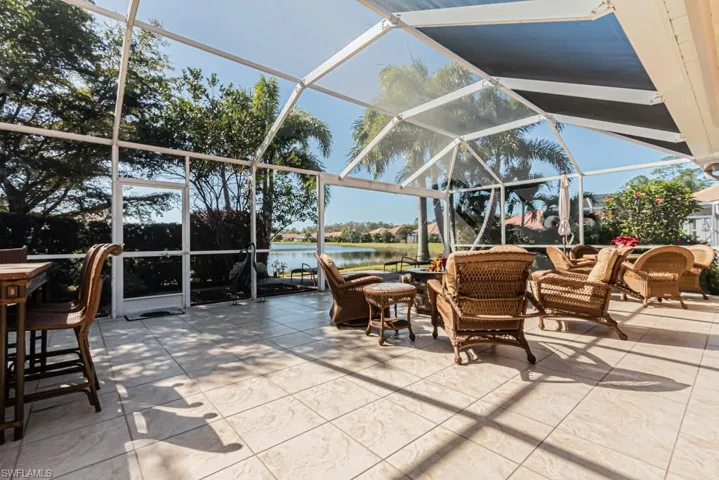 View of patio / terrace featuring an outdoor living space, glass enclosure, and a water view