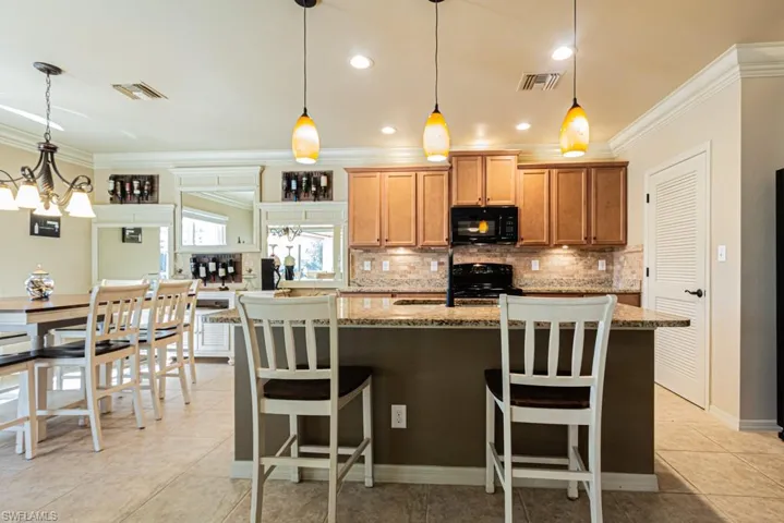 Kitchen with decorative light fixtures, a center island, a kitchen breakfast bar, and black appliances