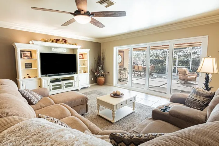 Tiled living room featuring ceiling fan and ornamental molding