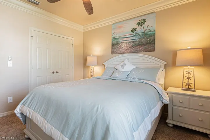 Bedroom with dark colored carpet, ornamental molding, ceiling fan, and a closet