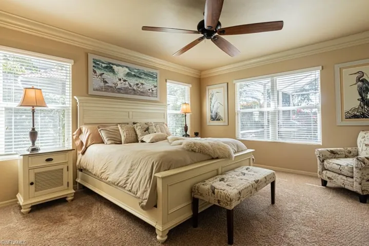 Carpeted bedroom featuring multiple windows and ornamental molding
