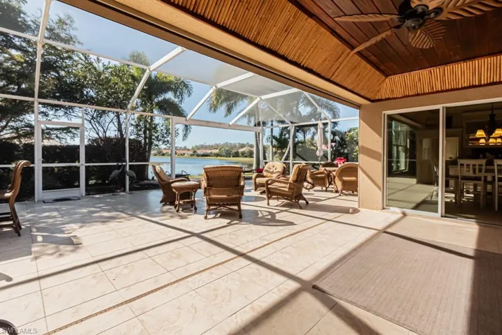 View of patio with ceiling fan, a water view, and glass enclosure