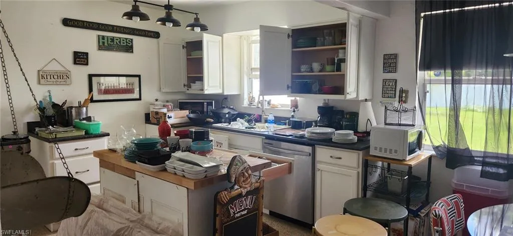 Kitchen with white cabinetry, sink, and stainless steel dishwasher