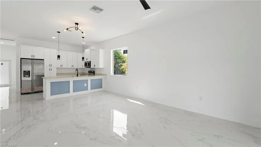 Kitchen featuring white cabinets, stainless steel appliances, open floor plan, pendant lighting, and a peninsula