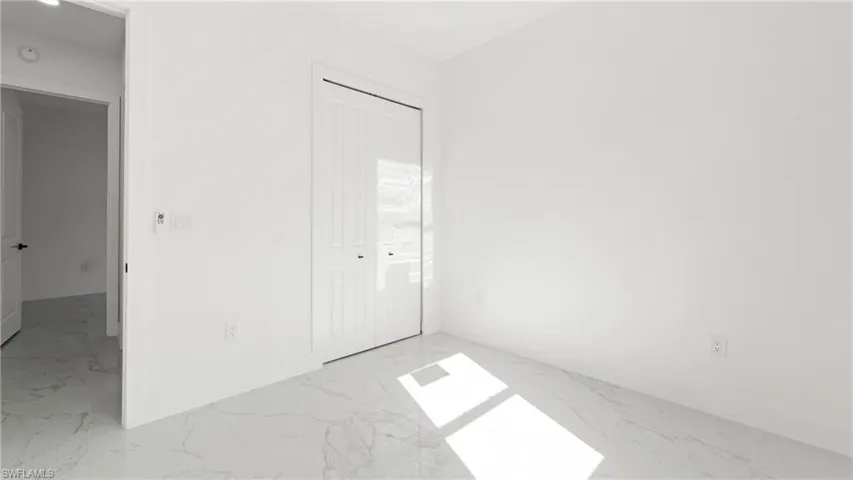 Unfurnished bedroom with a closet and light marble finish flooring