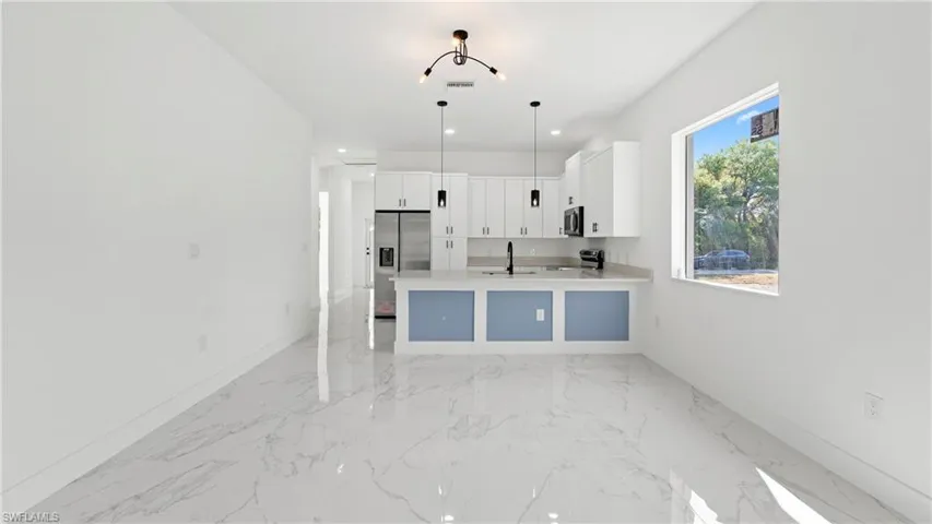 Kitchen featuring white cabinetry, pendant lighting, a peninsula, stainless steel appliances, and open floor plan