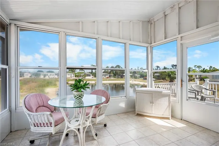 Enclosed porch featuring ceramic tile flooring, multiple windows, a corner built-in cabinet, and an exterior door leading to a deck