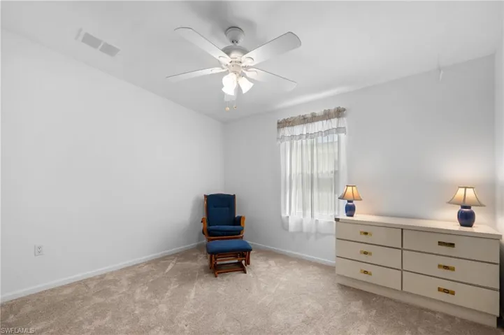 Neutral wall paint with carpet flooring, a ceiling fan, and a window with sheer curtains