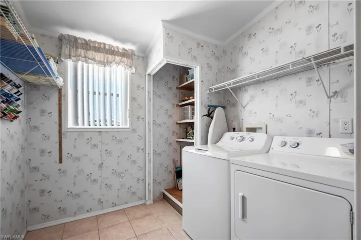 Laundry area featuring a window with vertical blinds, tile flooring, built-in shelving, and a dedicated storage nook